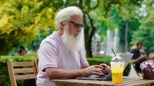 Good Looking Old Man Take His Laptop at the Cafe