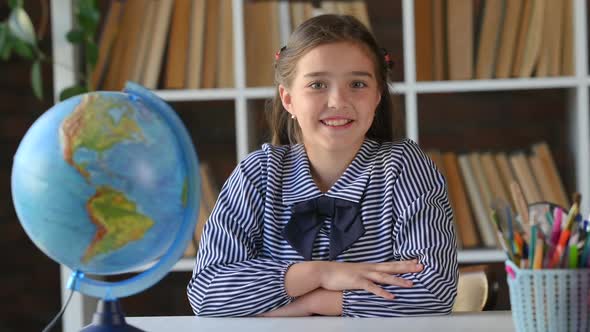 Portrait of a young hispanic schoolgirl primary school student sitting at her desk