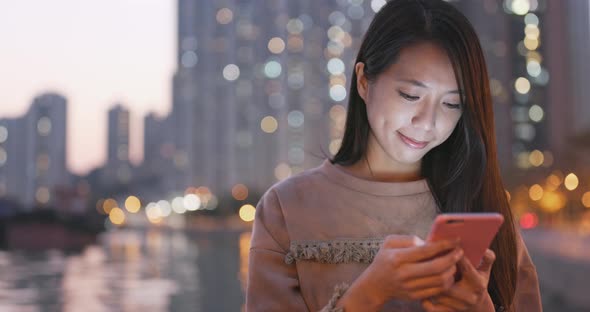 Woman use of mobile phone in city in the evening