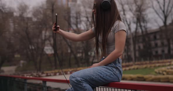 Happy Girl Making Selfie Sitting on Fence