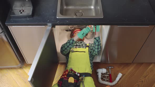 Top View of Professional Plumber Fixing Sink in Kitchen