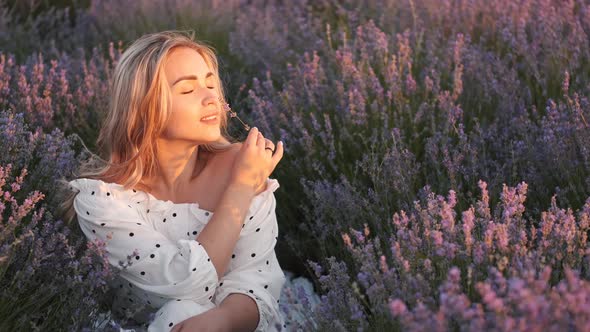 Pretty Blond Woman in a Dress Sitting in the Lavender Field