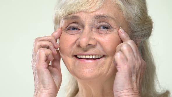 Smiling Old Woman Stretching Eye Wrinkles Up, Face Contouring Anti-Aging Massage