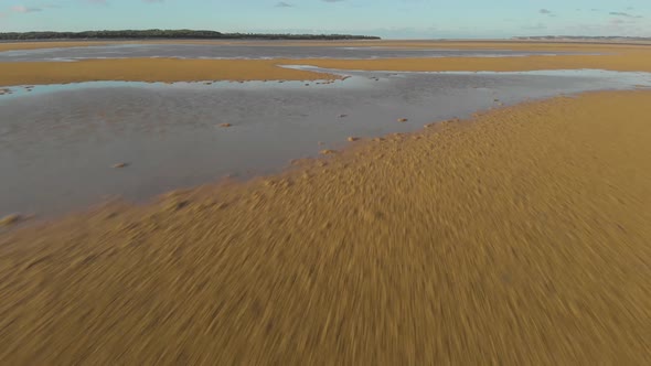 A fast low flying aerial shot of the sand and water at an inlet in Victoria Australia.