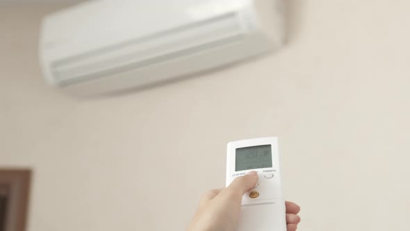 Woman Using Aircondition with Remote Control in Hotel Room
