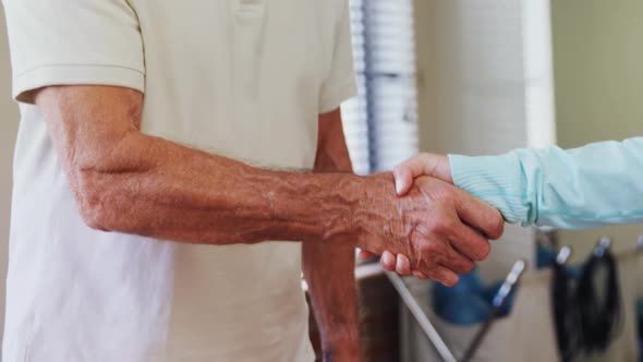Senior man shaking hand with physiotherapist