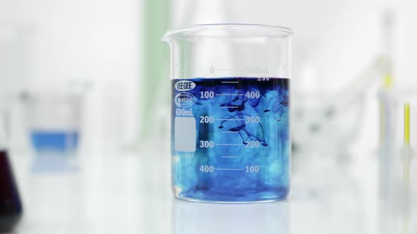 Panning view of beaker mixing blue liquid