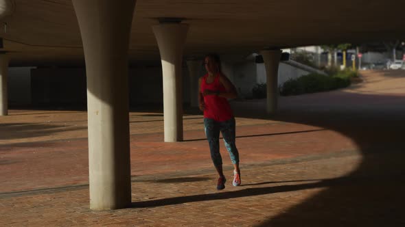 Caucasian woman running under a bridge