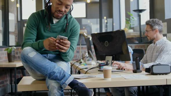 Smiling male executive using mobile phone at desk in office 4k