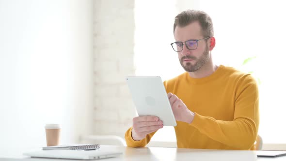 Man Reacting to Loss on Tablet in Office