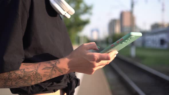 Person Writes a Message on the Phone on the Background of the Railway