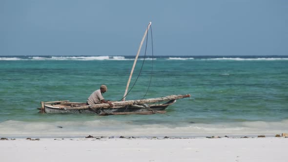 African Fisherman on an Old Dry Wooden Boat Sail in Ocean at High Tide Zanzibar