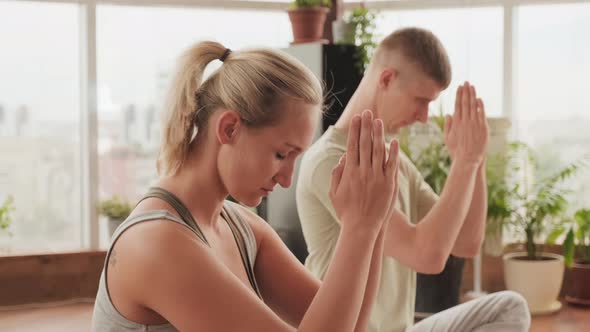 Couple Practicing Prayer Position At Yoga Class