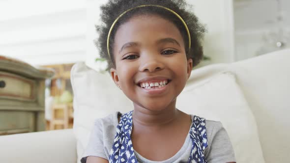 Portrait of smiling african american girl looking at camera in living room