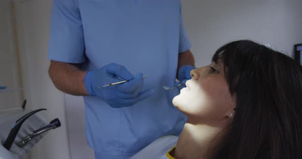 Caucasian male dentist examining teeth of female patient at modern dental clinic