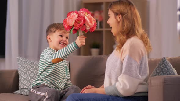 Smiling Little Son Gives Flowers To Mother at Home