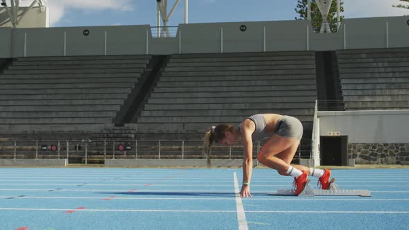 Side view of caucasian athlete preparing for race in stadium