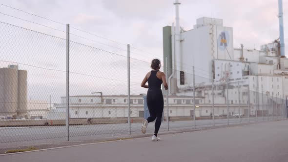 Young Woman In Black Sportswear Jogging Along Harbour