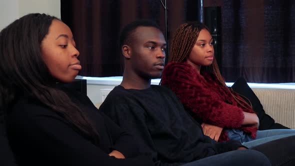 Three African Friends Come To Sit and Watch Television Together in Living Room