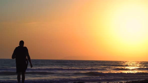 Young Man with Backpack Walking on Beach During Summer Vacation