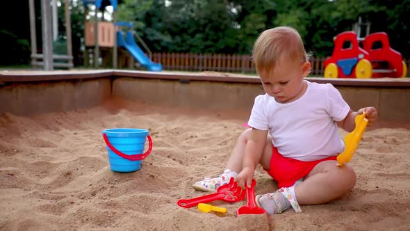 Adorable Toddler Girl Playing with Sand on Sandbox in Playground