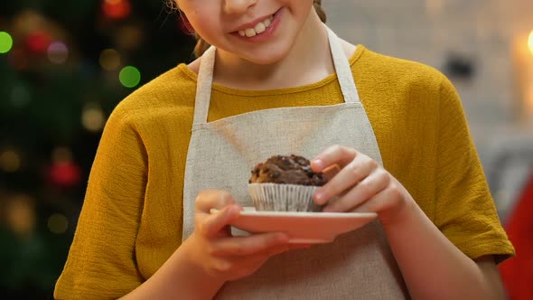 Girl in Apron Holding Cupcake, Smiling at Camera, Happy Christmas Childhood