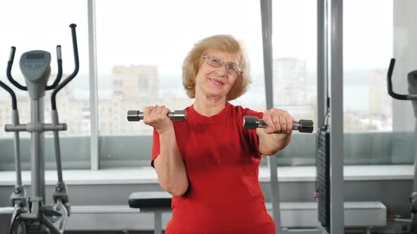 Elderly Woman Doing Training Weightlifting Exercising with Dumbbells in Gym