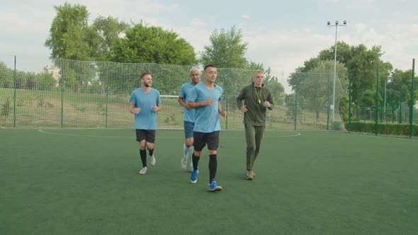 Team of Soccer Players Running with Coach Outdoors at Dawn