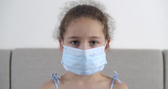 Portrait Cute Small Child or Little Girl in a Protective Medical Mask with a Sad Disappointed Face