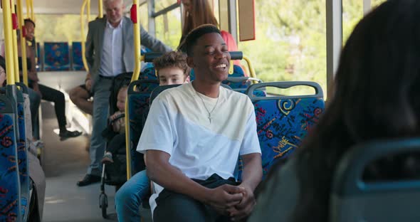 A Young Man in a White Tshirt Sits on a Public Transport Bus in Front
