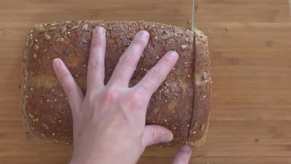 Cutting slices of a load of whole wheat and seed bread