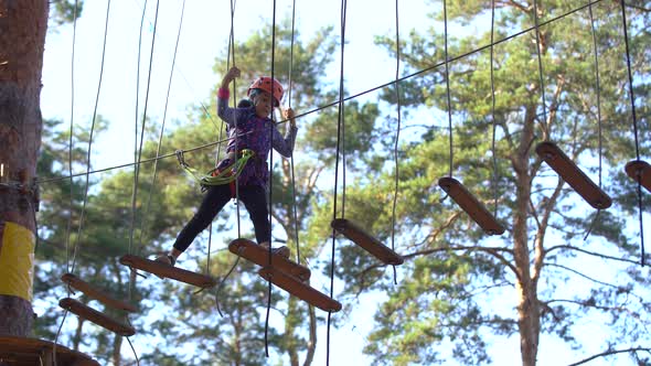 Little Girl is Standing on a Rope Holding a Rope with His Hands