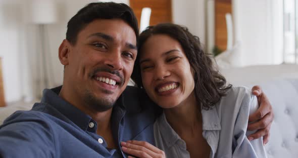 Portrait of happy hispanic couple embracing on sofa in living room