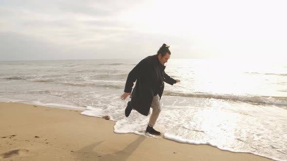 Attractive Brunette Man Running on the Wild Autumn Beach at Sunset