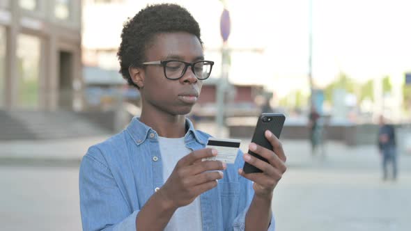 Excited Young African Man Shopping Online Via Smartphone Outdoor
