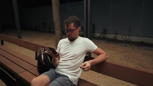 Adult Man Is Viewing News of Social Nets By Mobile Phone in Evening in Park