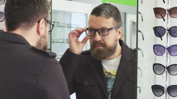 Mature Man Trying on New Glasses in Front If the Mirror at the Store