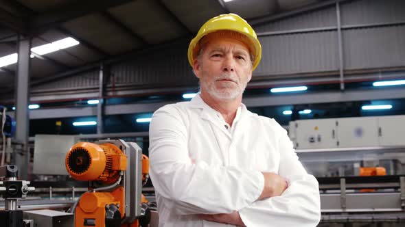 Worker standing with arms crossed in factory