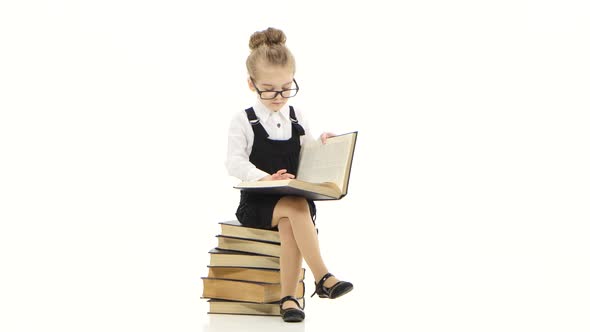 Smart Little Girl Is Studying an Encyclopedia Sitting on Books
