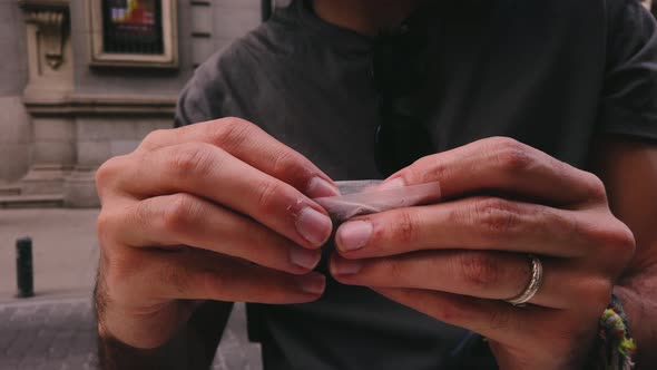 Slow-mo Rolling a tobacco cigarette in 4k. Close-up in slow motion of a cigarette being rolled. Man