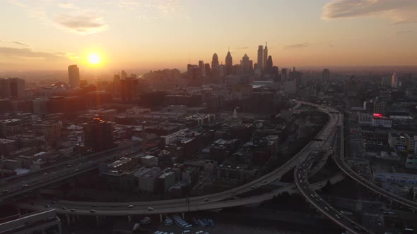 Aerial view moving forward showing the Philadelphia skyline and highways with cars and traffic durin