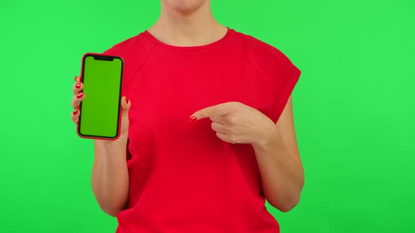 Woman in Red Tshirt Demonstrates Mobile Phone with Workspace Mock Up Screen on Green Background