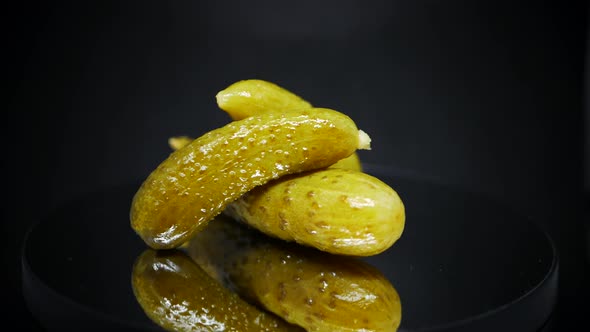 Three Pickled Gherkins Spinning Over Black Background - Fermented Cucumbers. - close up