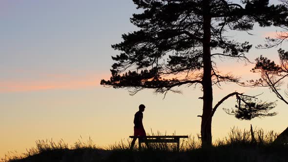 Silhouette of Lonely, Depressed Man, Sitting Down on Bench, Sunset Colors
