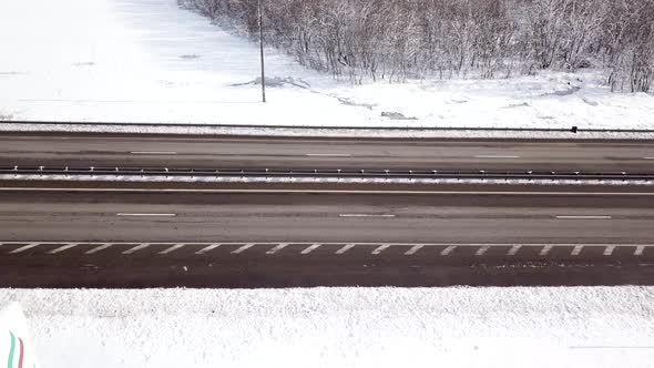 Winter Time Aerial Top Down View of a Snowy Road Surrounded Pine Tree Forest