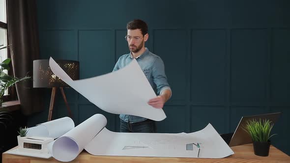 Close Up Shot of Young Man Hands Engineer Opening the Paper and Checking the Construction Drawings