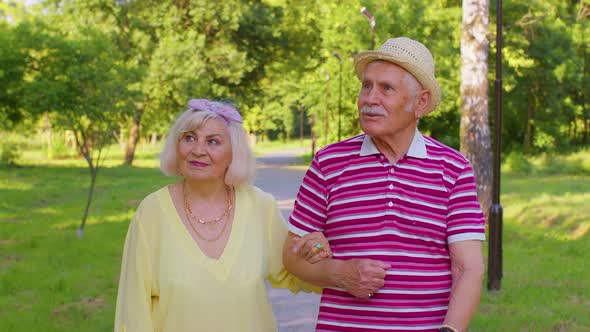 Senior Old Stylish Tourists Couple Grandmother Grandfather Having a Walk and Talking in Summer Park