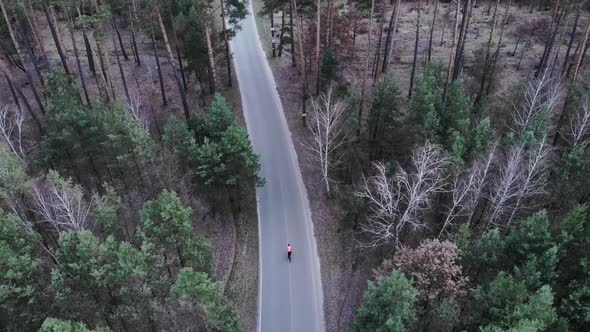 Professional cyclist is fast pedalling on road bike on empty car road in forest. Cycling concept