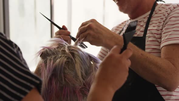 Close up view woman having her hair styled by two hairdressers