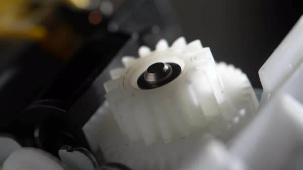 Gears rotating in mechanical device. Machine white plastic gears rotating